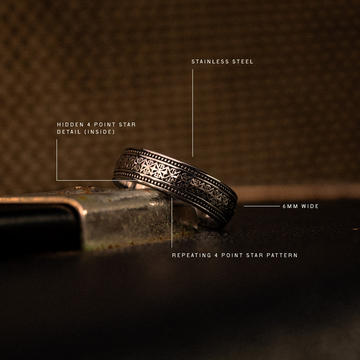 Stainless steel band ring, 6mm wide, with repeating 4-point star pattern and hidden detail on inner surface.