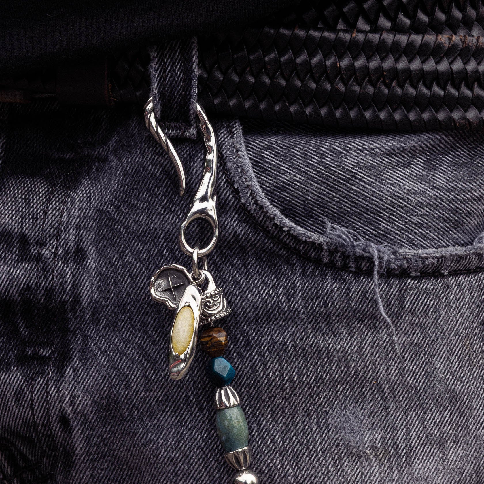 Silver keychain with dangling beads in cream, brown, blue, and green tones attached to black fabric zipper.