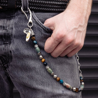 Silver wallet chain with multicolored beads and stone accents attached to denim pants pocket.