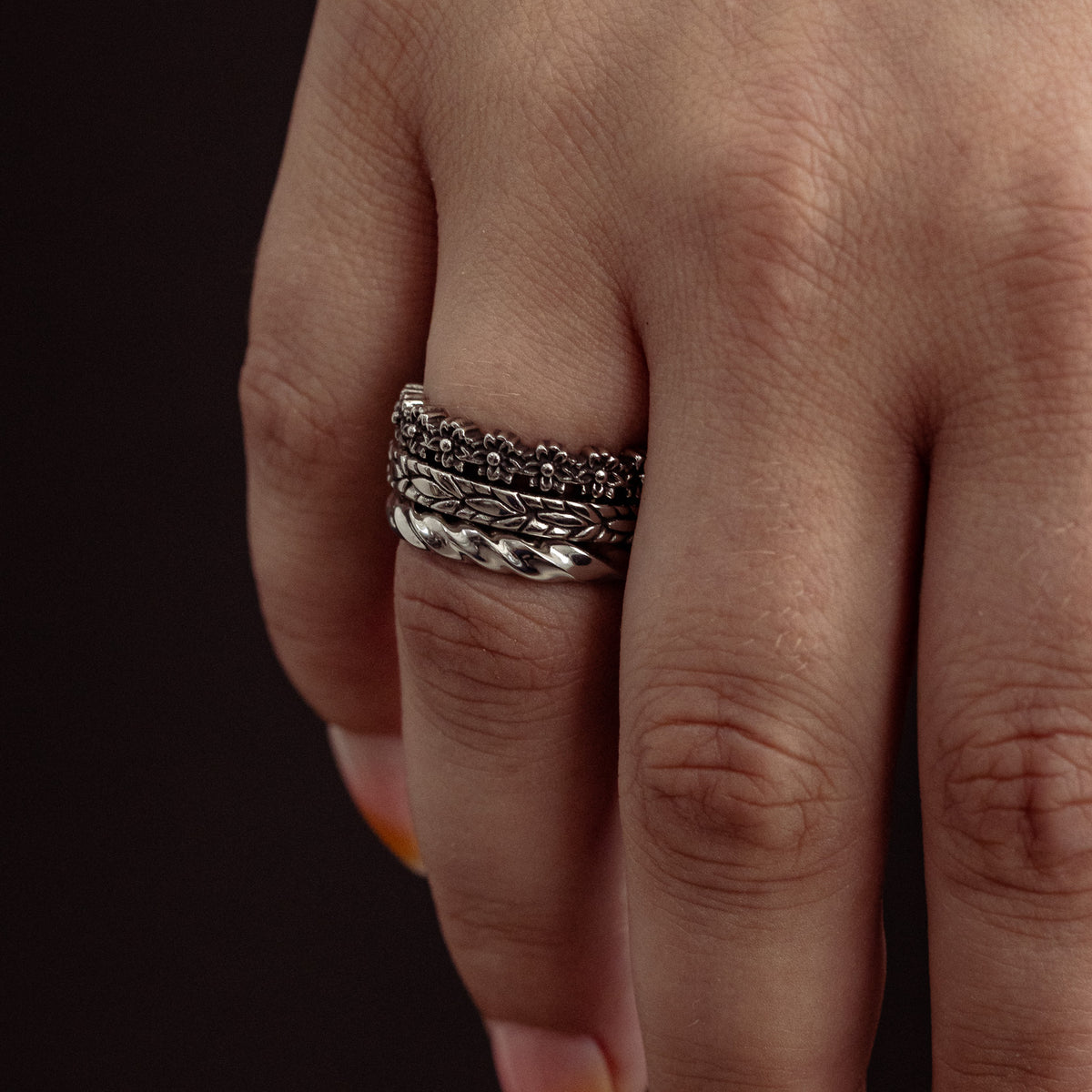 Silver stacked ring with textured and twisted bands worn on ring finger.