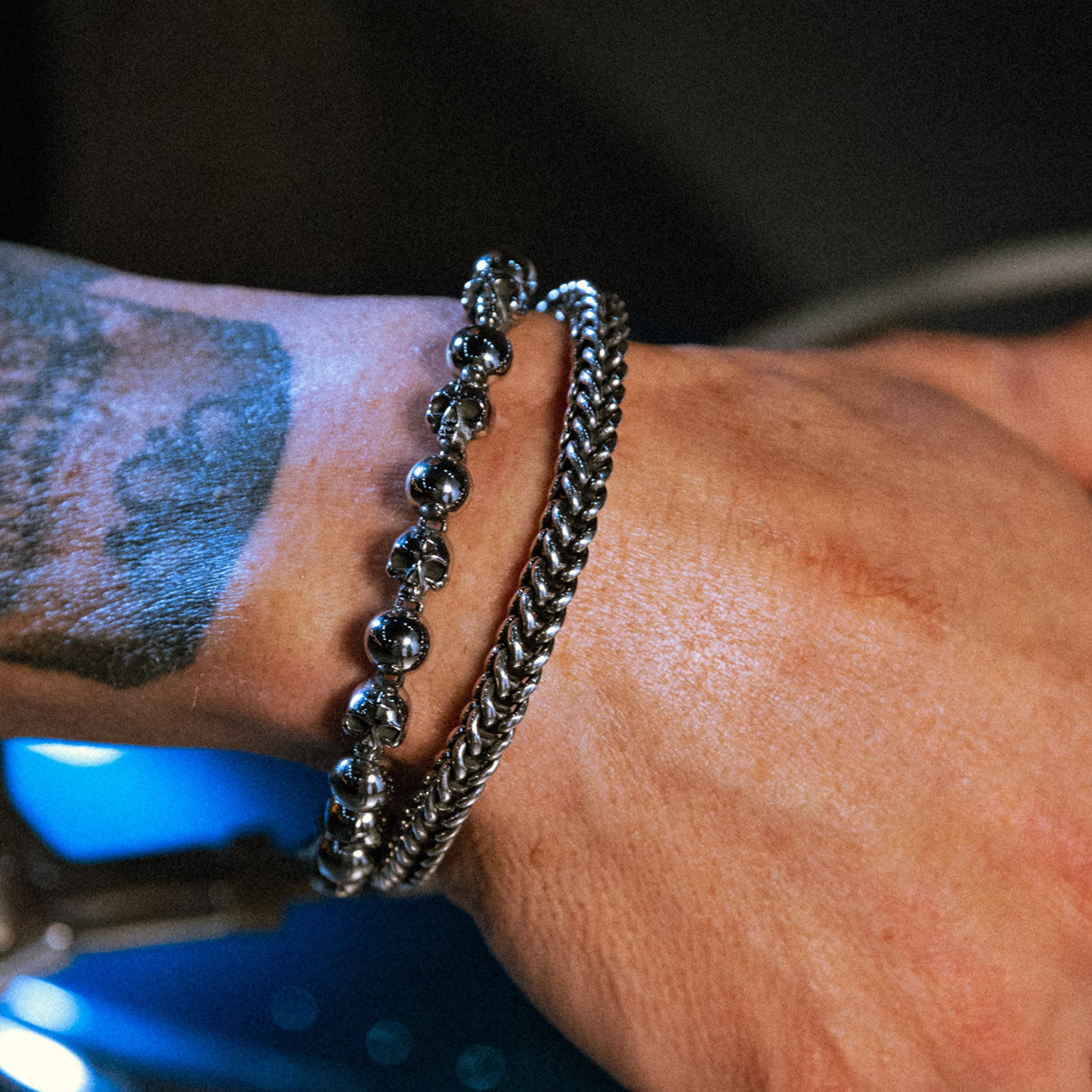 Close-up of a wrist wearing two silver bracelets with a blurred background