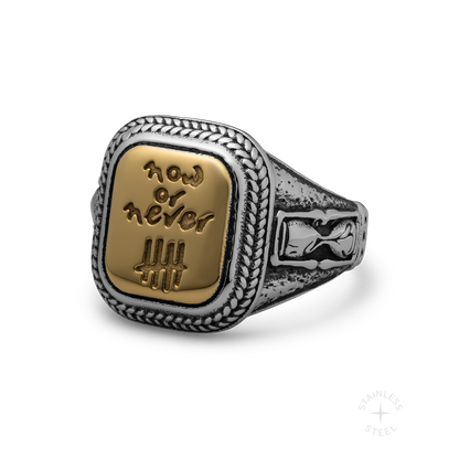 Silver and gold-tone ring with braided border and rectangular face engraved with "Now or Never" text and tally marks.