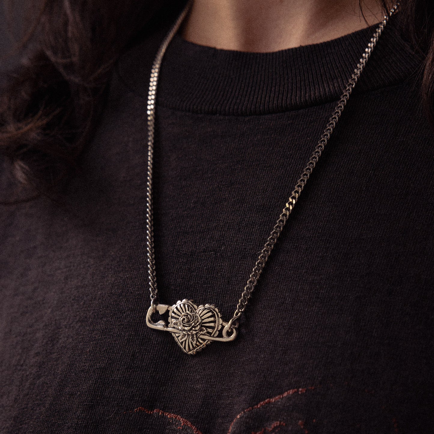 Silver chain necklace with ornate elephant head pendant worn on black ribbed sweater.