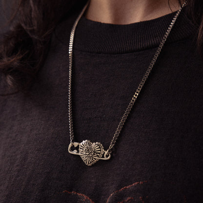 Silver chain necklace with ornate elephant head pendant worn on black ribbed sweater.