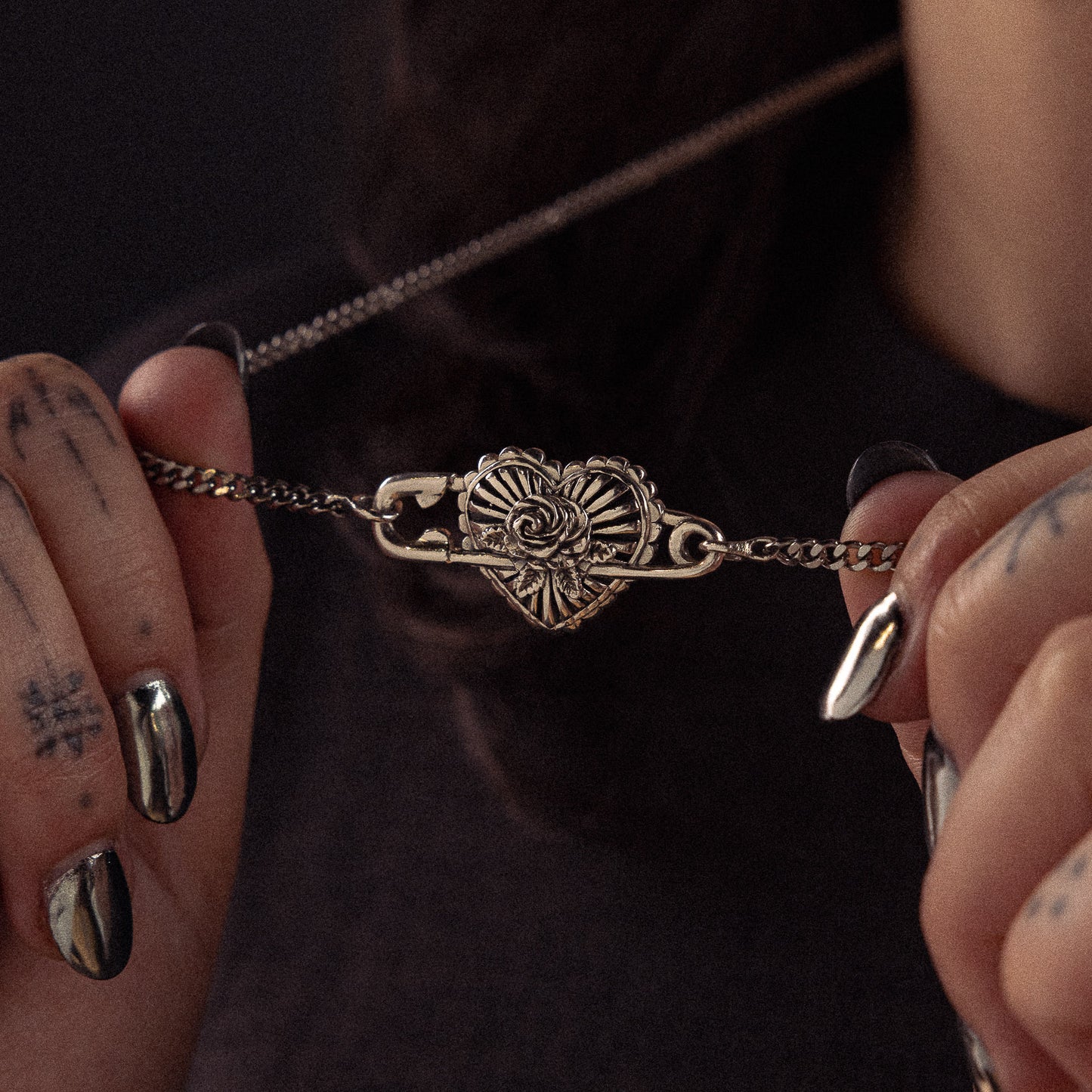 Gold-toned bracelet with ornate heart-shaped shell pendant held in hands against dark background.