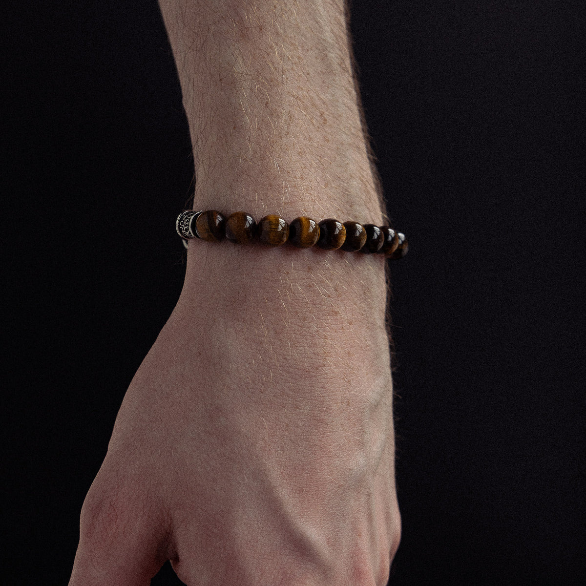 Beaded bracelet with golden-brown tiger's eye stones and metallic spacer accents worn on wrist.