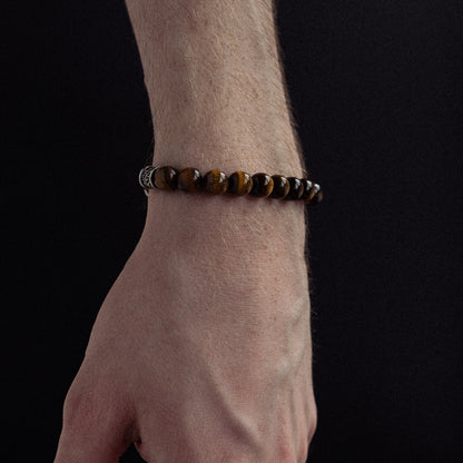 Beaded bracelet with golden-brown tiger's eye stones and metallic spacer accents worn on wrist.