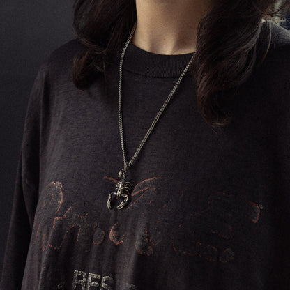Black t-shirt with distressed graphic print and silver skeleton scorpion pendant necklace.